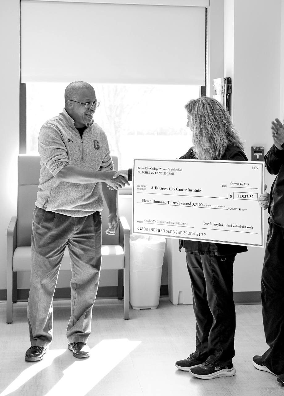 Coach Sayles presents the over $11,000 check to AHN.